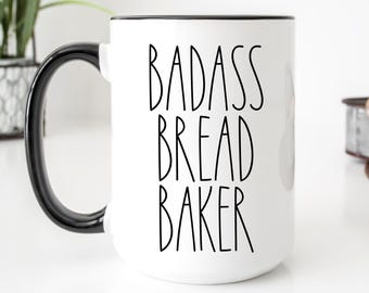 May include: White ceramic mug with a black handle and rim. The mug features the words "BADASS BREAD BAKER" in black, bold, sans-serif font. The mug is a standard size and is suitable for hot or cold beverages.
