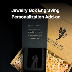 May include: A black jewelry box with a personalized engraving. The engraving says "My most brilliant achievement was my ability to be able to persuade my wife to marry me". The box is open and shows a silhouette of a couple inside. The box is made by Ma Petite Fee.