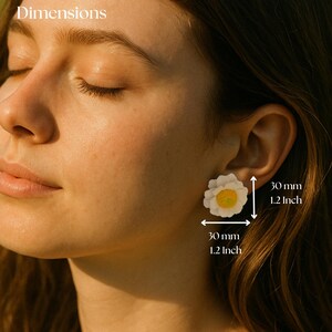 以下が含まれることがあります： 中央が黄色の白い花形のスタッドピアスで、サイズは30mm x 30mmです。このピアスは重なり合った白い花びらと質感のある黄色い芯が特徴で、耳たぶに装着された状態で30mmという寸法が記載されています。