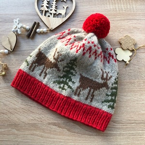 May include: A beige knitted hat with a red pom pom and a reindeer pattern. The hat has a red band around the bottom.
