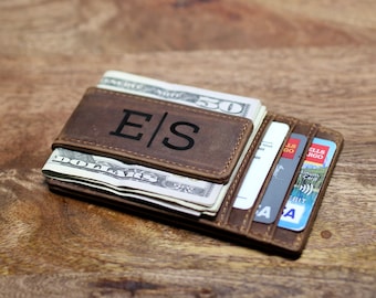 May include: A brown leather wallet with a money clip and card slots. The wallet has the initials "E|S" embossed on the front.