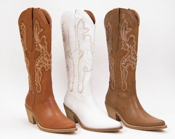 May include: Three pairs of cowboy boots in brown, white, and tan leather. Each boot has a pointed toe and a decorative embroidered design.