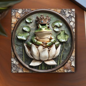 May include: A square, framed relief sculpture featuring a green frog wearing a crown, seated on a white lotus flower. The frog is surrounded by lily pads and a circular frame. The background has a stone-like texture.