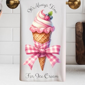 May include: A white kitchen towel with a pink and white ice cream cone with a pink bow and the text "It's Always Time For Ice Cream".