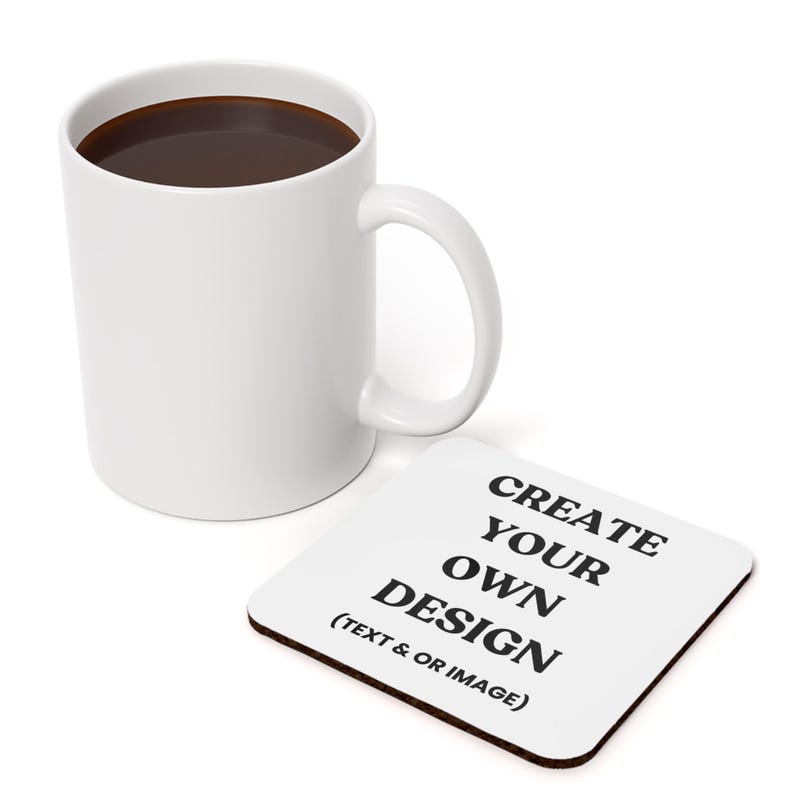 A white ceramic mug with a black handle filled with brown coffee. The mug is sitting on a white coaster with black text that reads 'CREATE YOUR OWN DESIGN (TEXT & OR IMAGE)'