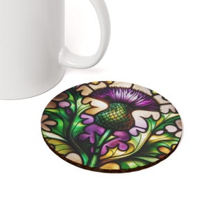A round coaster with a stained glass design of a purple thistle flower with green leaves and a yellow background.