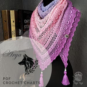 May include: A beautifully crafted crochet shawl in a gradient of purples and pinks, shown on a mannequin. The shawl has a delicate, openwork design and is finished with tassels and beads. The image includes the text "Arya Shawl" and "PDF Crochet Charts".