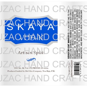 May include: A white label with the text "SKAYA" in white letters on a blue background. The label also includes the text "Artisan Spirit" and a government warning about alcohol consumption. The label is for a product from Del Oro Company, Toa Baja, P.R.
