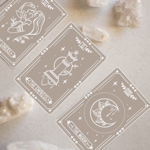 May include: Three tarot cards with white outlines on a beige background. The cards are "The Lovers", "The Empress", and "The Moon".