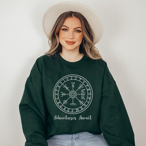 May include: A dark green sweatshirt with a grey compass design and the text "Adventures Await".