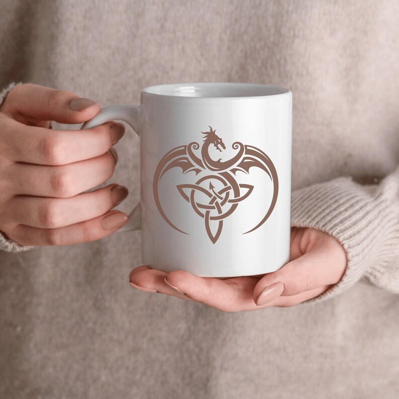 May include: White ceramic mug with a brown dragon and Celtic knot design.