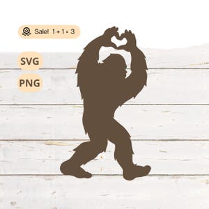Op de afbeelding: Een bruin silhouet van een Bigfoot die een hartvorm maakt met zijn handen.