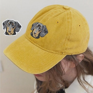 May include: A yellow baseball cap with an embroidered dachshund dog on the front.