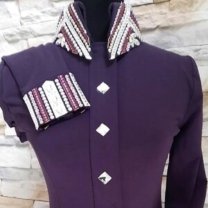 Peut inclure: Une chemise &agrave; manches longues de couleur violette avec un col et des poignets orn&eacute;s de blanc et de rose. La chemise a une fermeture boutonn&eacute;e &agrave; l'avant et une silhouette ajust&eacute;e.