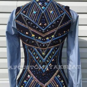 May include: A black show vest with a geometric design featuring blue, gold, and silver rhinestones. The vest has a fitted silhouette and a high back. The text "AFCUSTOMBYAKSHAT" is printed on the bottom of the vest.
