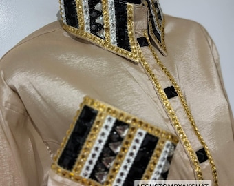Camisa de seda color champán con detalles de pedrería negra y dorada y almohadilla de lana.