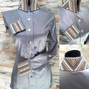 Peut inclure: Une chemise &agrave; manches longues en satin gris avec un col et des poignets d&eacute;coratifs. Le col et les poignets sont orn&eacute;s de strass, de perles et de paillettes dans des tons de brun, blanc et argent.
