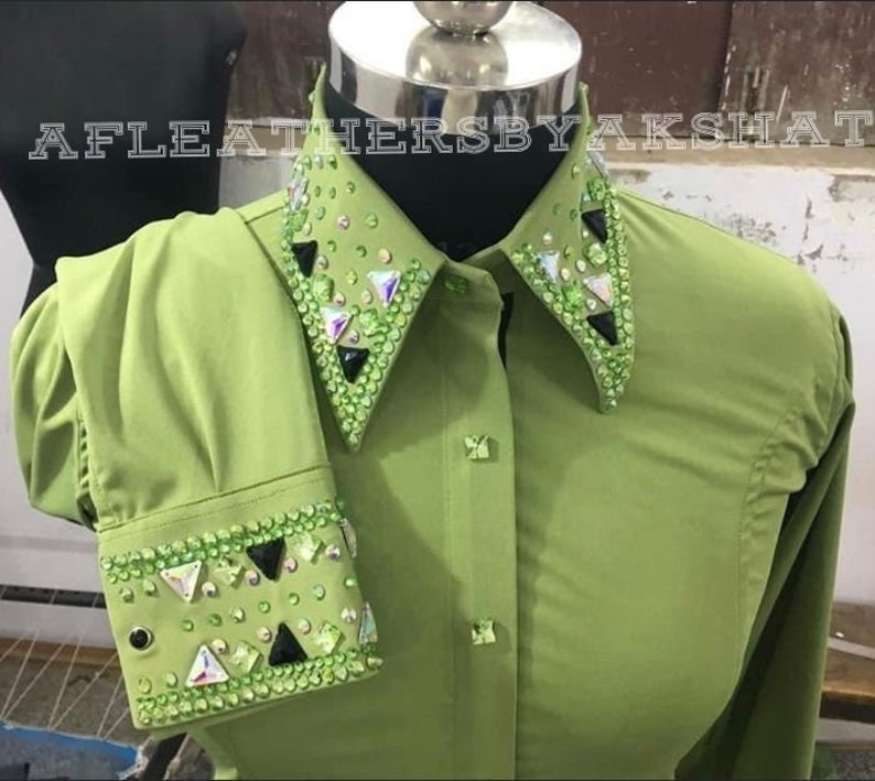 May include: A green button-down shirt with a large embellished collar and cuffs. The collar and cuffs are decorated with rhinestones and black triangular accents.