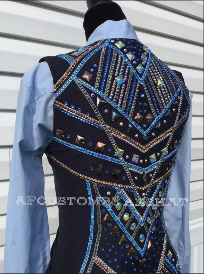 May include: A navy blue show vest with a geometric design featuring blue, silver, and copper rhinestones. The vest has a  "AFCUSTOMBYAKSHAT" label on the bottom.