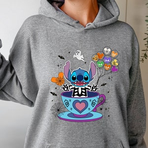 May include: Gray hooded sweatshirt with a blue Stitch character wearing a skeleton costume and holding balloons. Stitch is sitting in a teacup with a heart design. The design includes bats, spiderwebs, and a ghost.