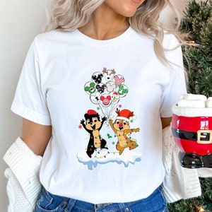 May include: White t-shirt with a Christmas-themed design featuring two cartoon characters holding balloons with various Disney characters on them. The characters are Chip and Dale, and the balloons have Mickey Mouse, Minnie Mouse, Donald Duck, Goofy, and Pluto on them.