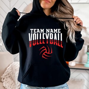 May include: Black hooded sweatshirt with a white and red graphic print of a volleyball and the text "TEAM NAME VOLLEYBALL".