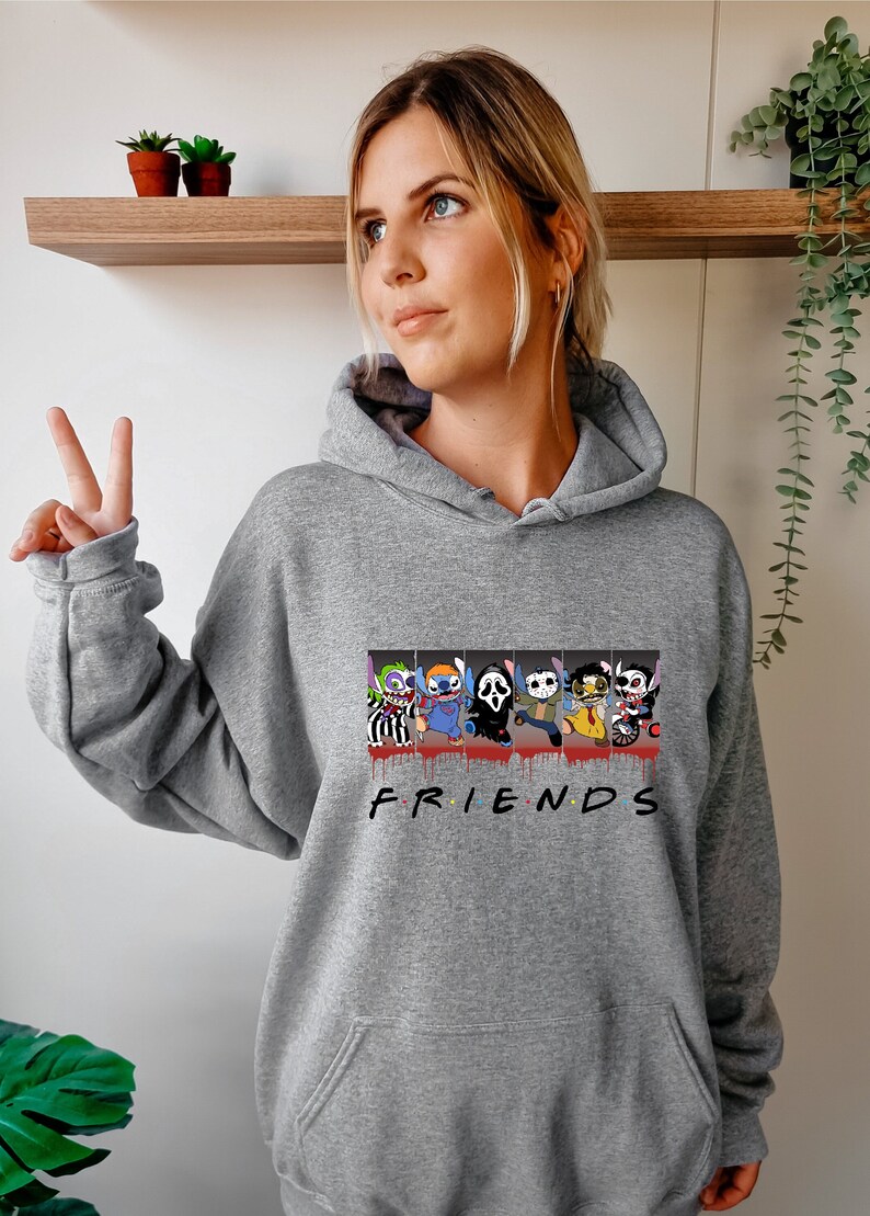 Op de afbeelding: Grijs hoodie met een grafische print van Stitch en andere horrorfilmfiguren. De grafiek bevat de tekst "FRIENDS" met druppels bloed.