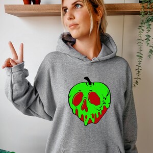 Op de afbeelding: Grijs hoodie met een groene appel print. De appel heeft een schedel gezicht met rode ogen en een druipend groen en rood ontwerp.