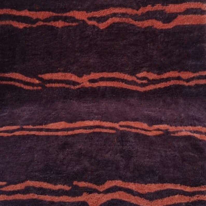 May include: A close-up of a dark brown and reddish-brown striped rug with a fuzzy texture.