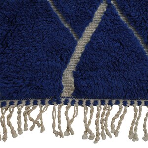 May include: Blue and white geometric patterned rug with a fringe border. The rug has a fluffy texture.