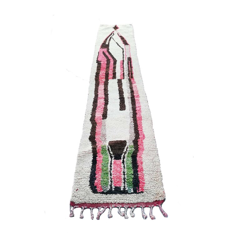 May include: A long, white rug with a geometric design in pink, green, and brown. The rug has fringe on the ends.