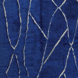 May include: Blue rug with a white geometric pattern. The pattern is made up of lines and shapes that create a modern and abstract design.