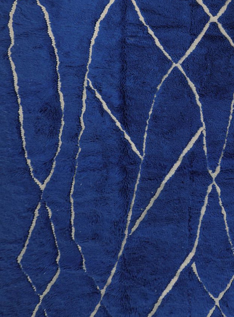 May include: Blue rug with a white geometric pattern. The pattern is made up of lines and shapes that create a modern and abstract design.