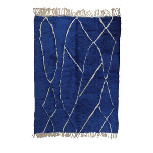 May include: A blue and white Moroccan rug with a geometric pattern. The rug has a fringe border.