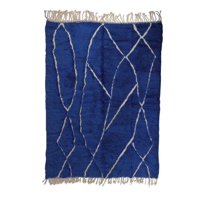 May include: A blue and white Moroccan rug with a geometric pattern. The rug has a fringe border.