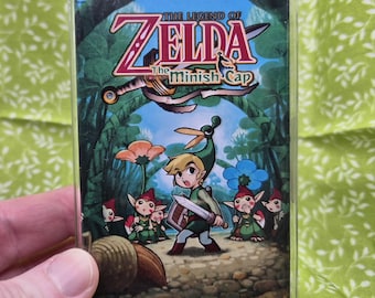 May include: A cassette tape for "The Legend of Zelda: The Minish Cap" soundtrack. The cover art shows a forest scene with game characters. The text "THE ORIGINAL SOUNDTRACK" is at the bottom.