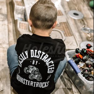 May include: A black t-shirt with a white graphic that says "Easily Distracted - By Monster Trucks".