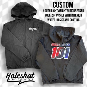 Könnte beinhalten: Schwarze Windbreaker-Jacke in Kindergröße mit durchgehendem Reißverschluss und Kapuze. Die Jacke hat eine wasserabweisende Beschichtung und trägt den Schriftzug "Holeshot Family Racing Gear" auf der Vorderseite und "MCCULLOUGH 101" auf der Rückseite.