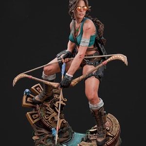 May include: A detailed statue of a woman in action, holding a bow and arrow. She wears a teal top, shorts, and boots, with sunglasses and a feather in her hair. The statue is on a decorative base with intricate carvings and a water feature.