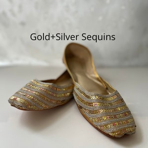 May include: A pair of gold and silver sequined flat shoes. The shoes have a pointed toe and are made of a soft, flexible material.