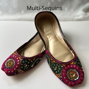 May include: A pair of flat, burgundy shoes with gold, green, and pink embroidery and sequins. The shoes have a pointed toe and a flat sole.