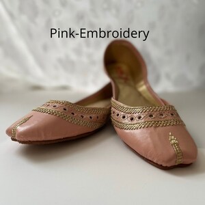May include: A pair of pink leather flats with gold embroidery. The shoes have a pointed toe and a flat heel.