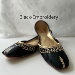 May include: Black leather flats with gold embroidery. The embroidery features a delicate pattern of teardrop shapes.