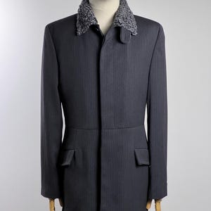 May include: A dark gray pinstripe jacket with a gray faux fur collar. The jacket has a single button closure and two flap pockets.