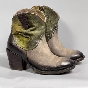 May include: A pair of brown and green leather ankle boots with a block heel. The boots have a distressed look and are made of different shades of brown and green leather.