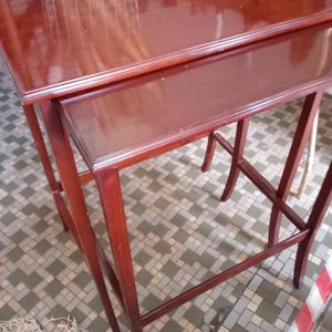 Op de afbeelding: Een set van twee houten nesttafels met een rijke bruine afwerking. De tafels zijn gemaakt van massief hout en hebben een eenvoudig, elegant ontwerp.