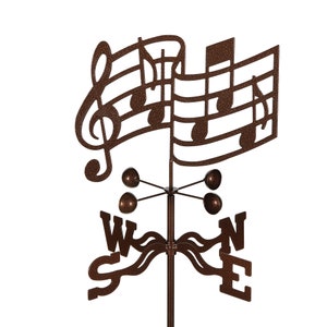 May include: A brown metal wind chime with a musical note design. The wind chime has four bells and a compass rose with the letters W, S, E, and N.
