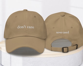 May include: A tan baseball cap with the text "don't care" embroidered on the front and "never cared" embroidered on the back.