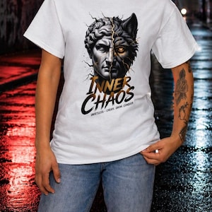 May include: White t-shirt featuring a split design of a classical bust and a wolf's head, with the text "INNER CHAOS" in gold. The shirt also includes the words "UNSETTLE - CREATE - GROW - CONQUER" in a smaller font.