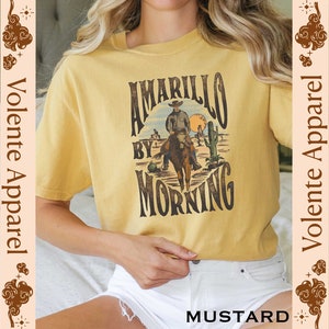 May include: A yellow t-shirt with a vintage graphic design featuring a cowboy riding a horse with the text "Amarillo by Morning".
